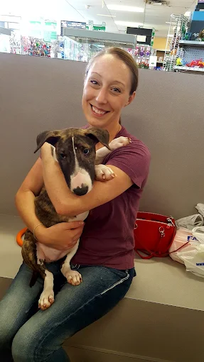 A woman holding a puppy in the store